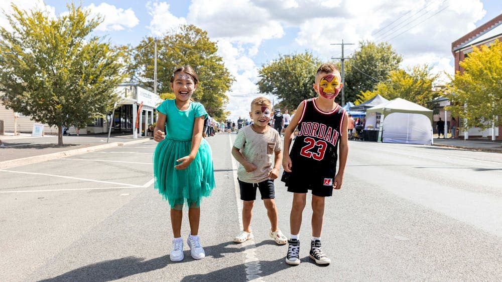 Three children jumping for joy at the Ballan Autumn Festival.