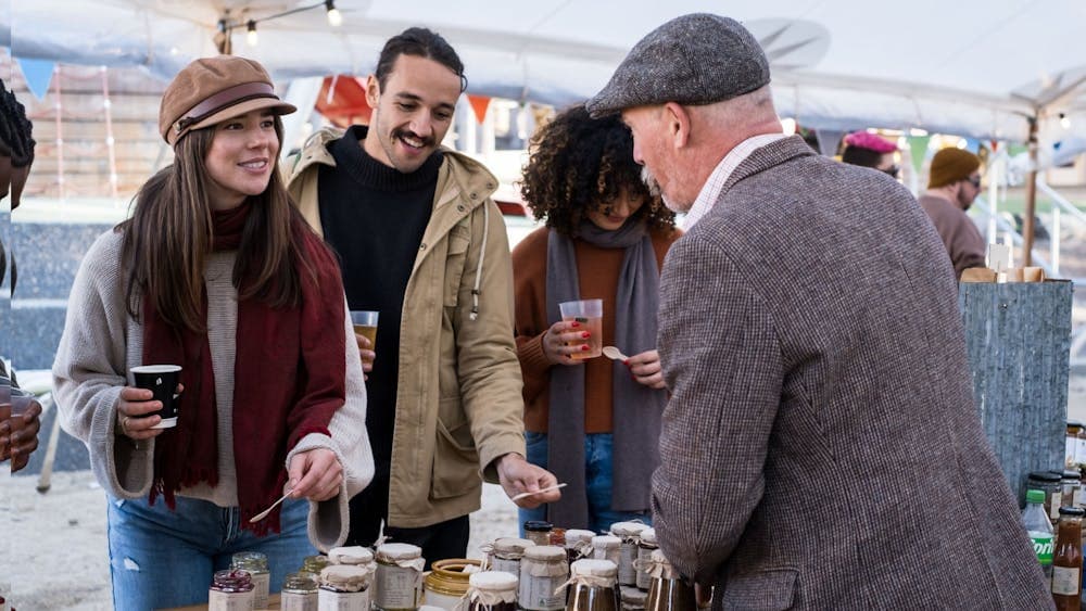 Group of 3 friends sampling tea at market stall