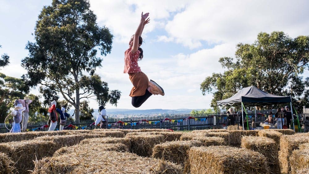Young girl jumping off hay bales