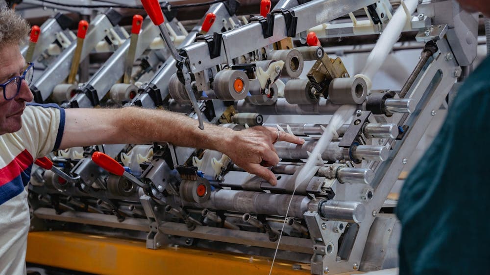 A hand is pointing at a roving just before it gets spun