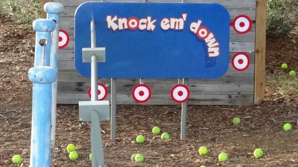 Multiple targets surrounding a rectangular board reading Knock Em Down with balls on the floor