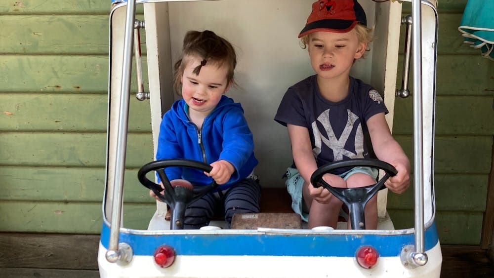Two children playing in a toy car