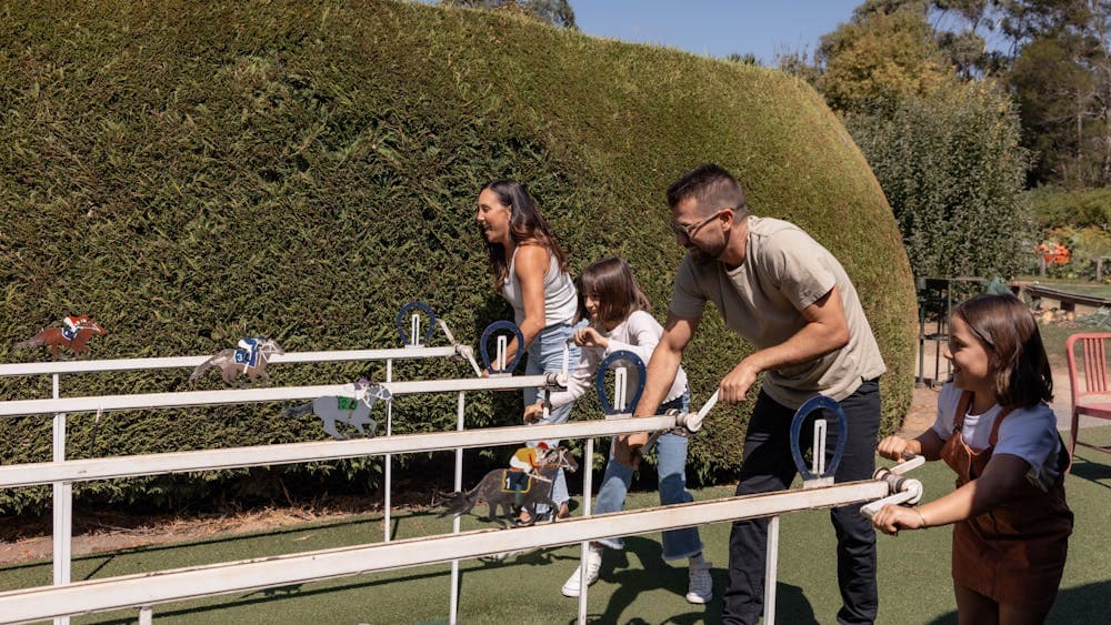 Family of four playing a wooden horse racing game