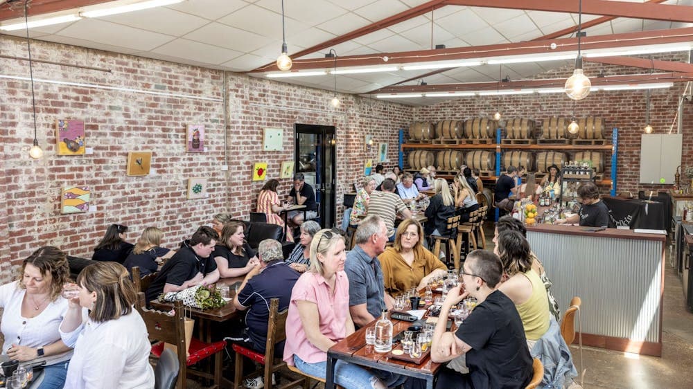 a crownded room of people at various tables enjoying each other's company