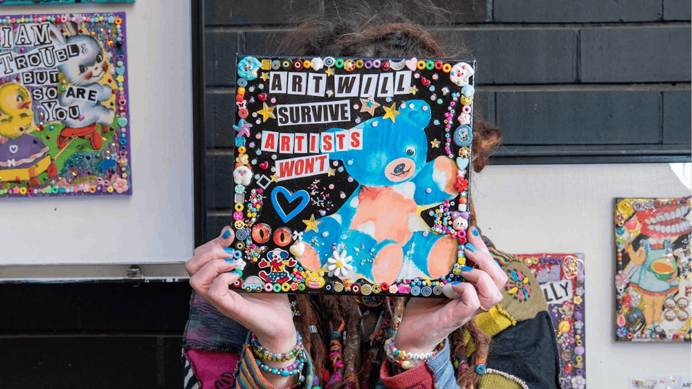 Artist holding their mixed media canvas work in front of their face so they can't be seen.