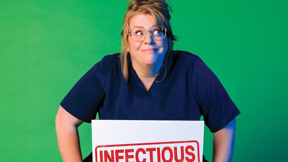 Nurse Georgie Carroll in her hospital scrubs with a sign reading 'infectious'