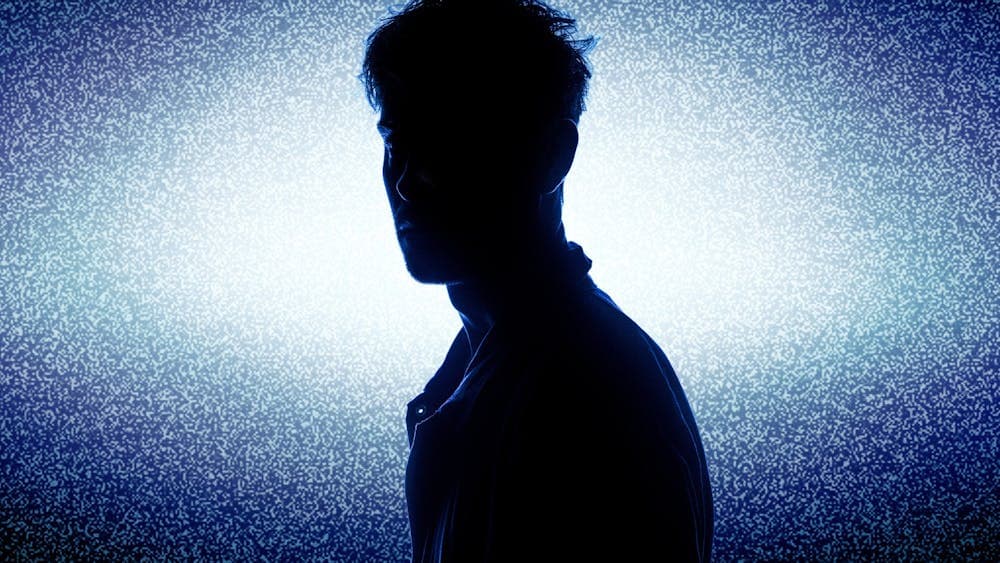 A lone figure silhouetted by a large screen of static