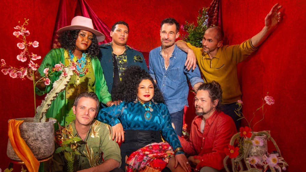 The whole band dressed up to the nines in front of a red curtain