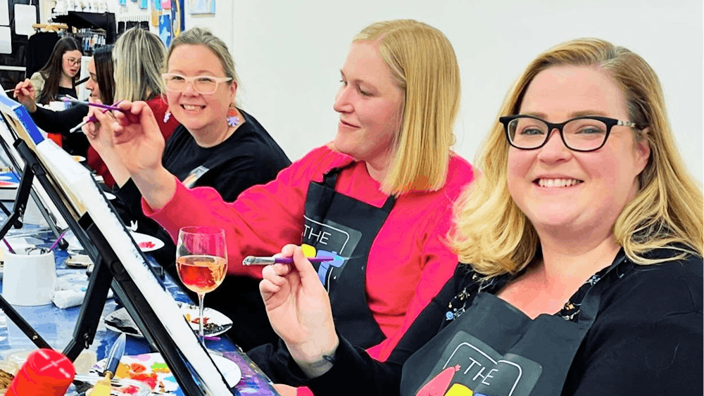 Women at a paint and sip event enjoying painting a canvas