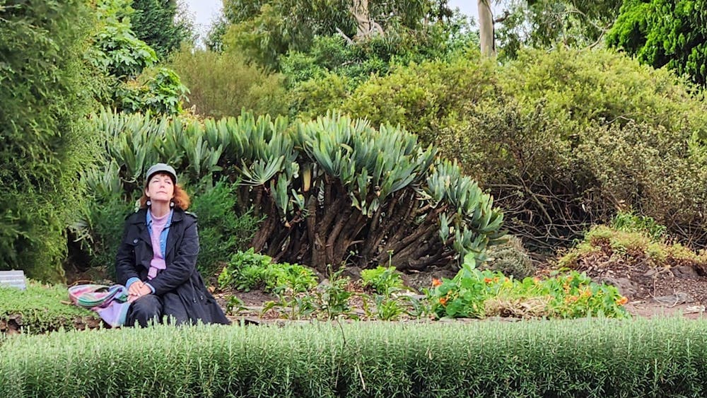 a woman sitting on a bench in a garden