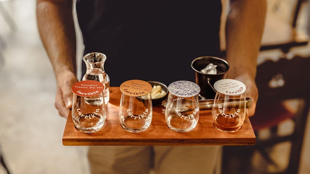 four small glasses of gin on a wooden board