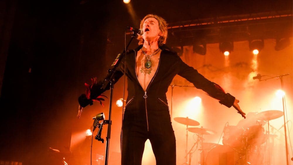 Tim Rogers with arms spread wide on stage