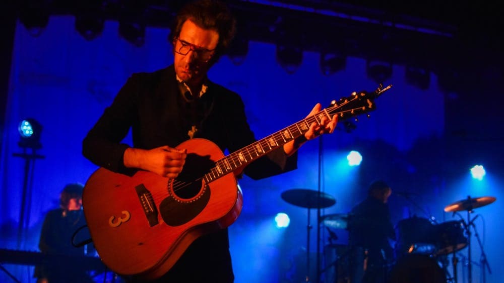 David Lane lit up with red light while he plays guitar