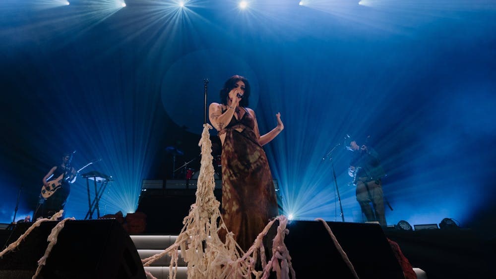 The captivating Thelma Plum singing on stage with a woven sculpture around her microphone stand.