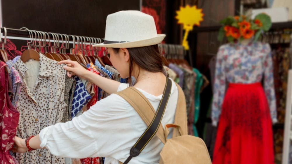 a woman looking through clothes on a clothes rack