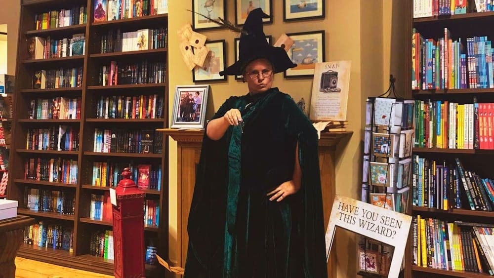 A staff member dressed as Professor McGonagall is pointing her wand at the camera