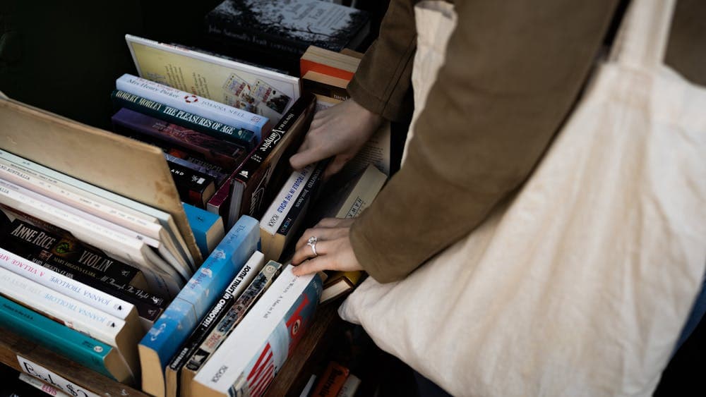A person holding a tote bag peruses a book stall.