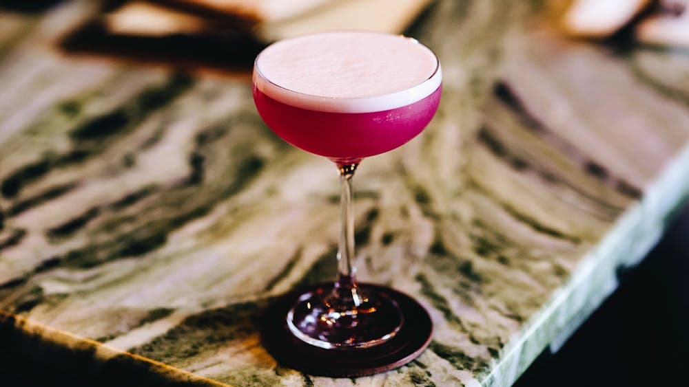 a pink cocktail in a glass on a marble bench