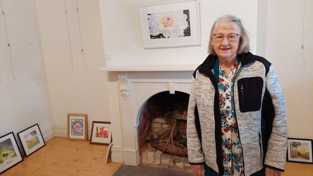 Lyn Thomas is pictured with her watercolor painting  of a summer flower.