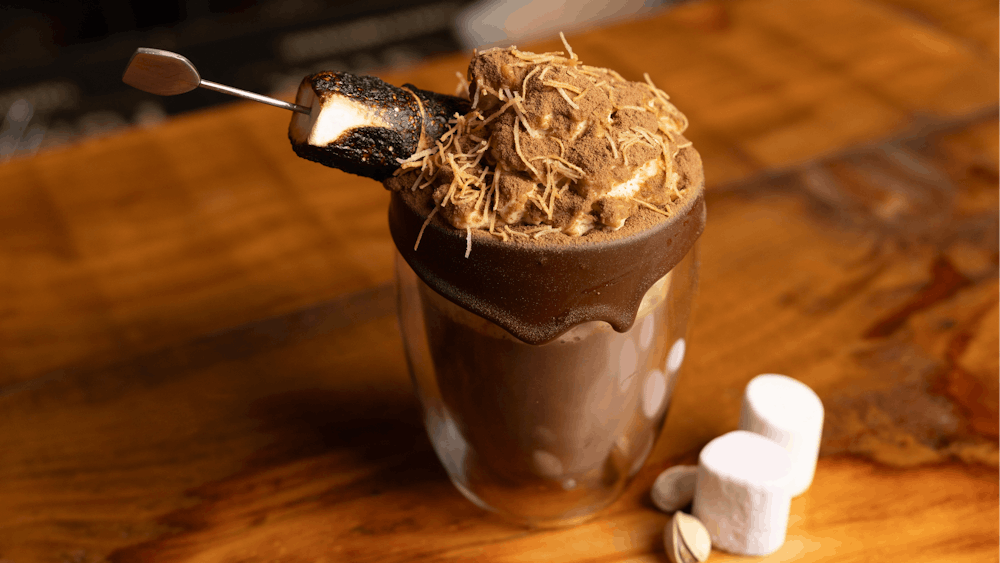brown hot chocolate in a double walled glass with a roasted marshmallow on top
