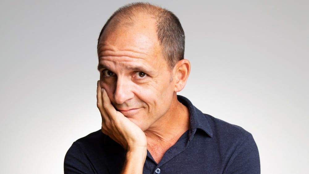 Carl looking coy in a navy polo on a grey background