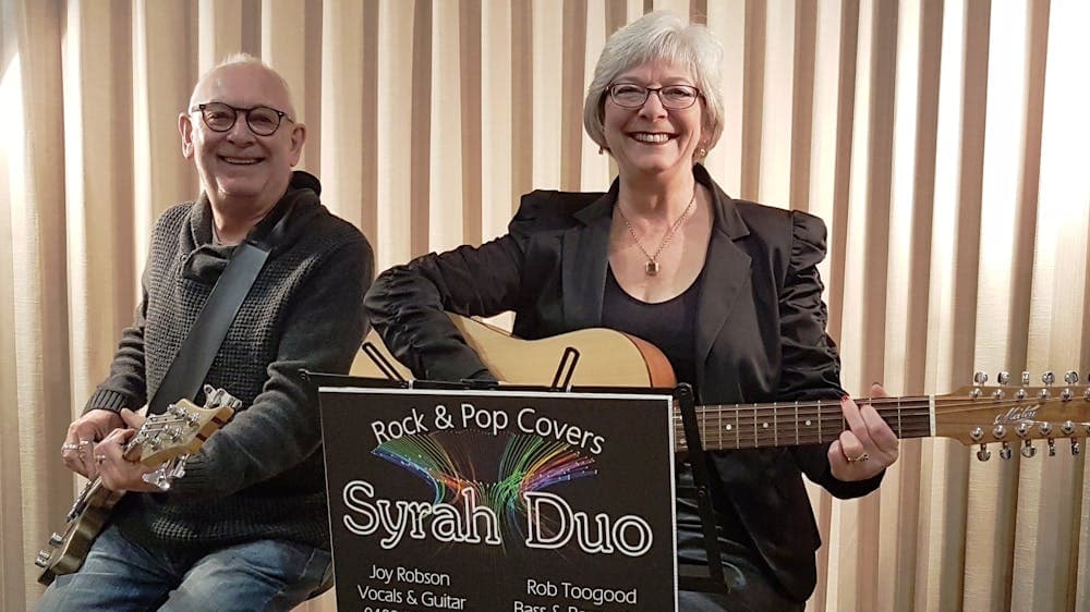 Syrah Duo Joy and Rob holding their guitars and smiling