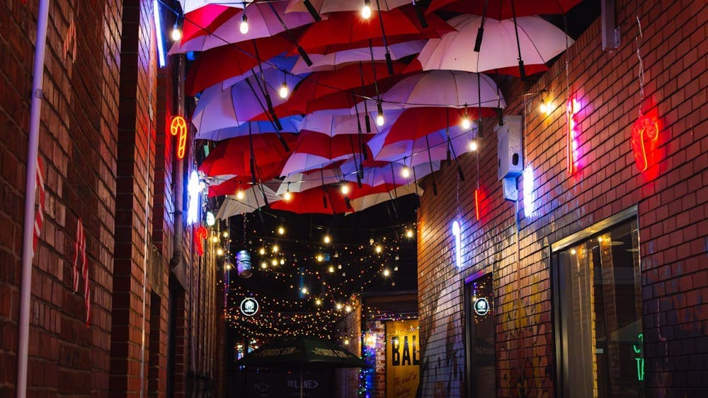 Red and white umbrellas lined up in an alley with Christmas lights