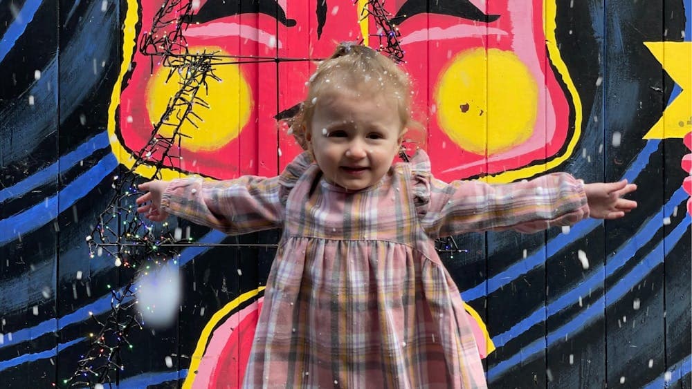 Young child posing in front of a colourful wall