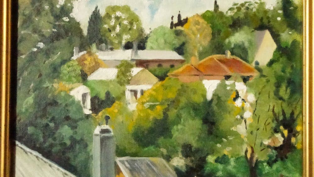 A view of  buildings some with red roof and tin snuggled into the bushy countryside