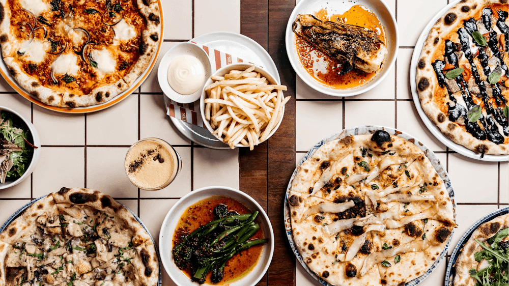 Pizzas and sides served on plates and placed on a table