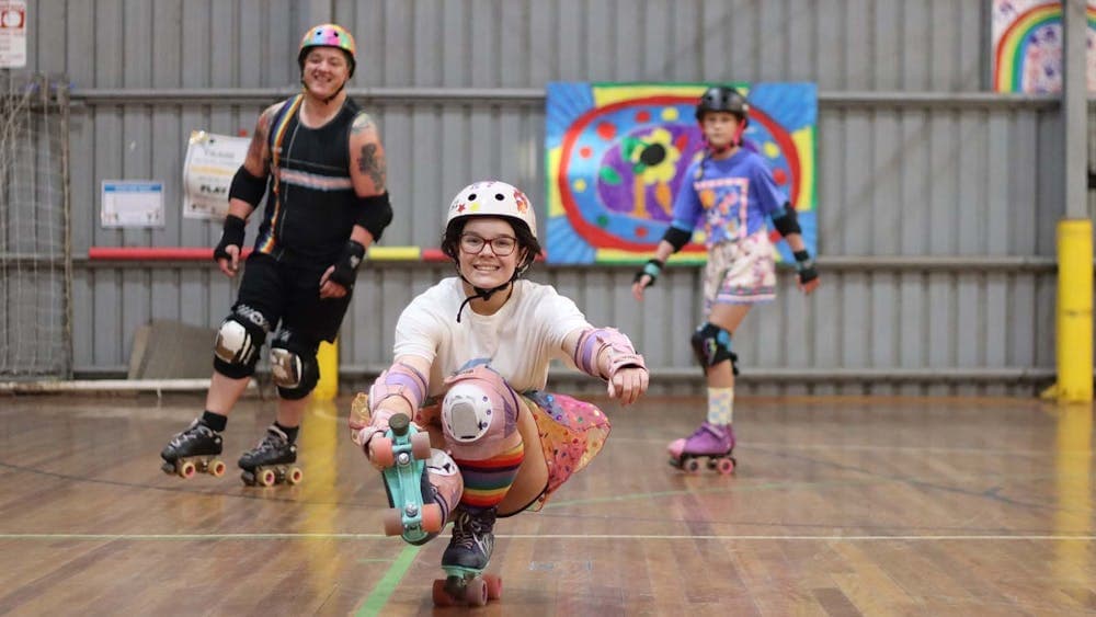 People Roller Skating in a stadium wearing bright coloured clothing