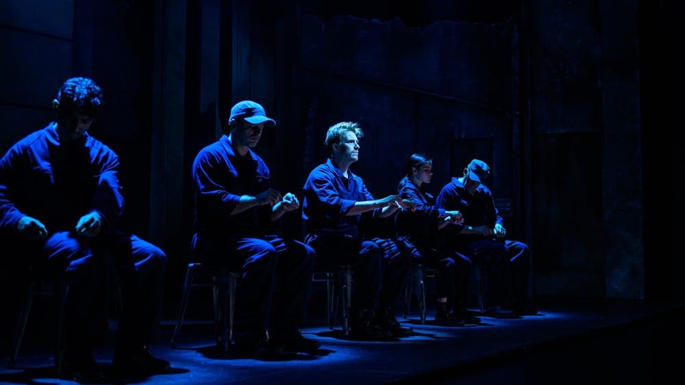 Winston seated amongst a line of prisoners working