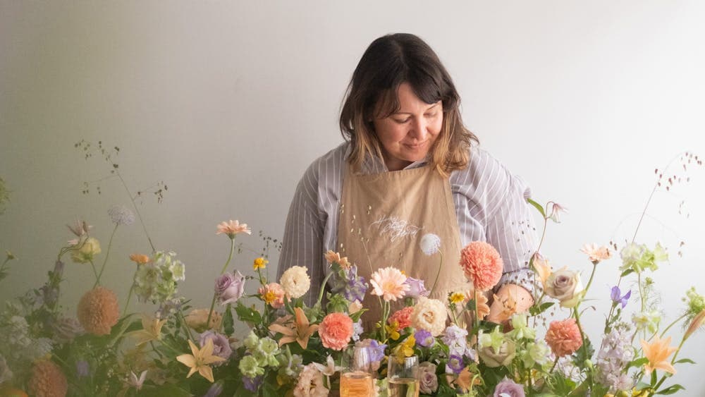 Woman in apron looking at table display of soft pastel flowers