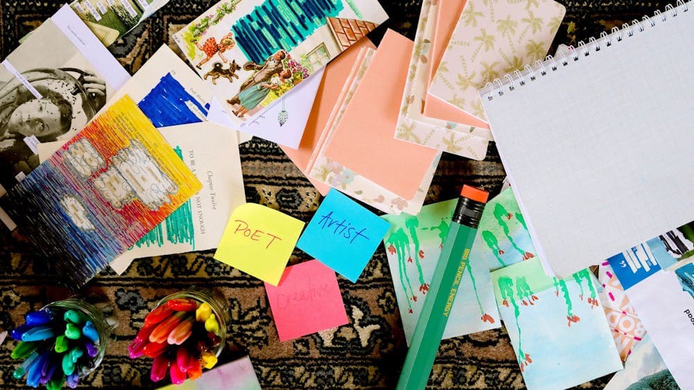 A collection of colourful collages, textas and an oversized pencil, colourful sticky notes.