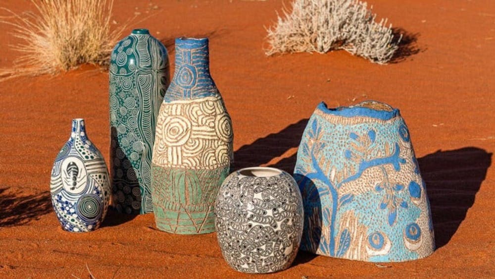 Five colourfully decorated vases on red dirt in the desert