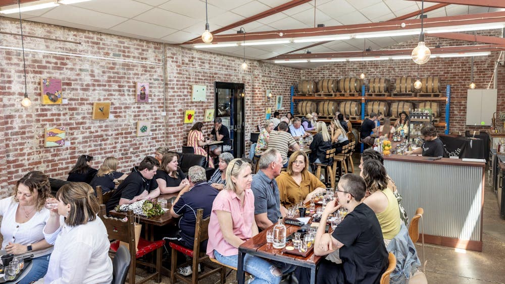A refurbished warehouse filled with people sitting at tables having conversations