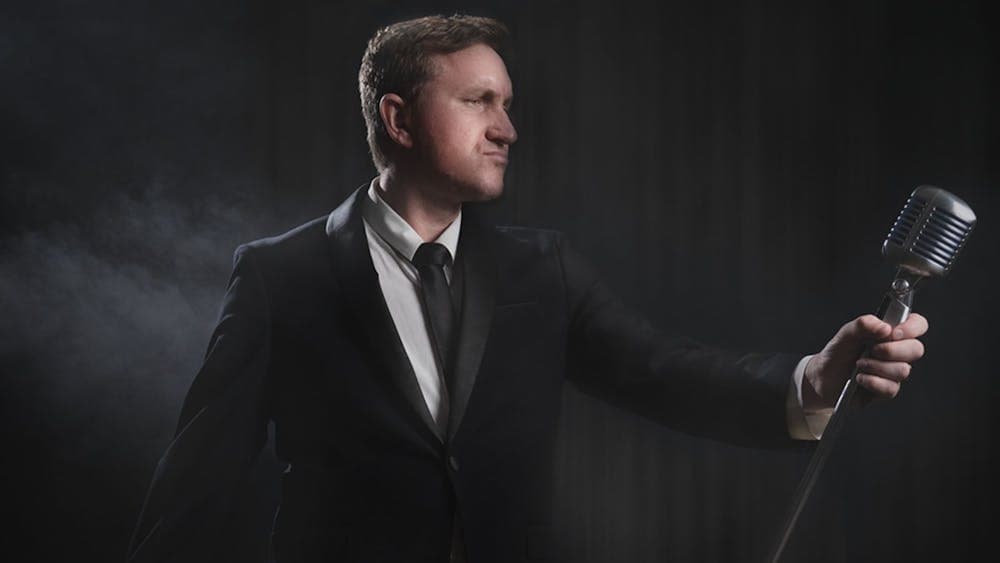 Glen Starr in a suit and holding an old style microphone