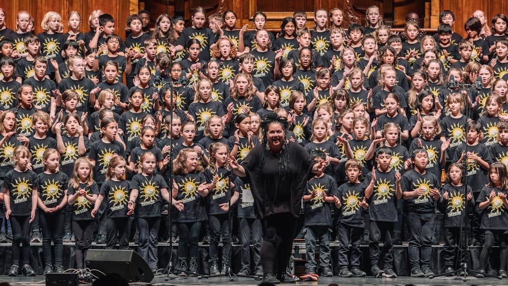 Children of The Boite Schools Chorus 2025 on stage singing in black t-shirts.
