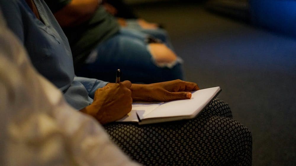 Detail of a person in a theatre writing into a notebook