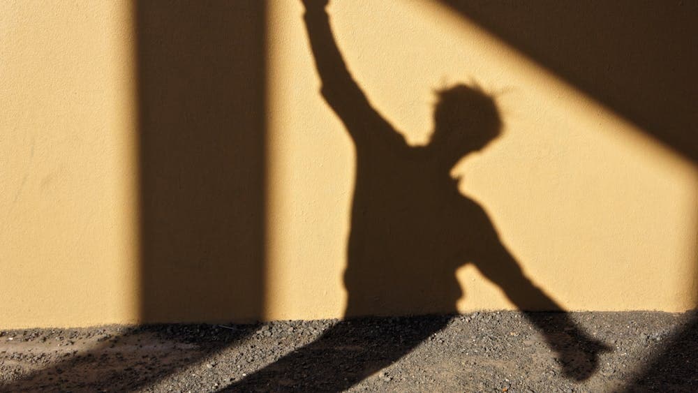 Dancing shadow of a person on a yellow wa