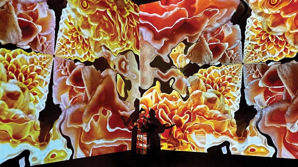Kylie Supski performing live, standing in front of immersive animated visual projections