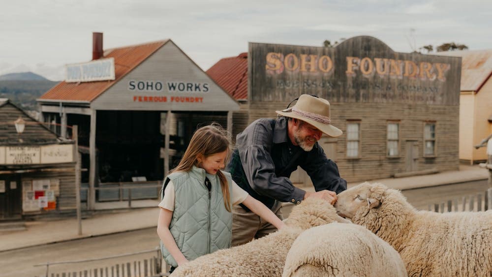 Girl patting sheep with costumed animal handler