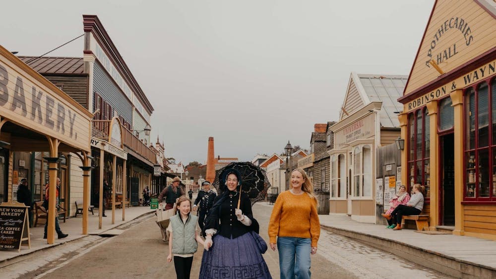 Mother and daughter walking with a costumed woman at Sovereign Hill Main Street