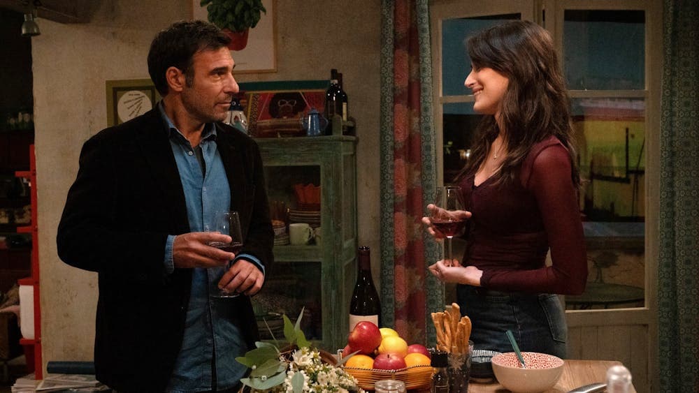 Couple stand in kitchen holding wine