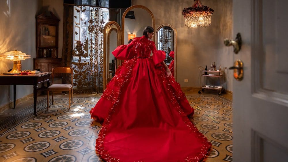 Woman stands in dress room in extravagant red dress