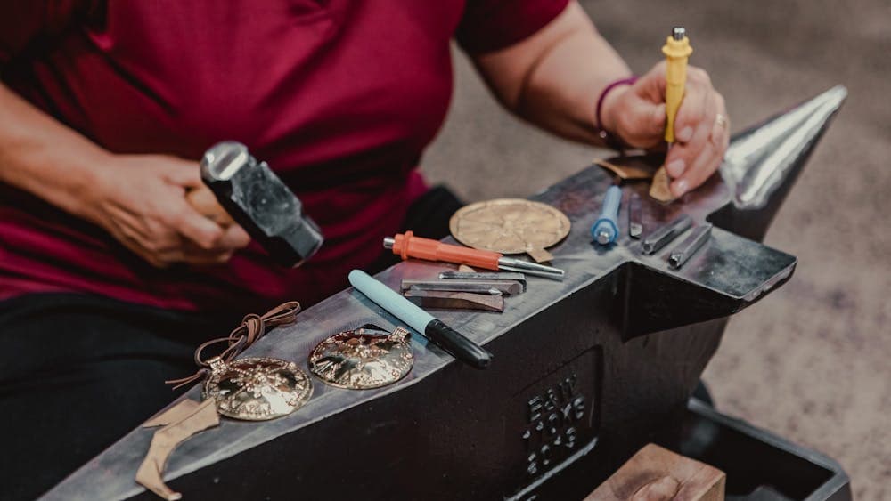 Close up of hands working with metal on anvil