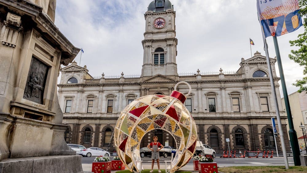 The giant Christmas Bauble sits in front of Town Hall with a little girl in red standing inside it