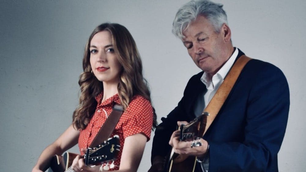 A mand and woman standing side by side holding guitars