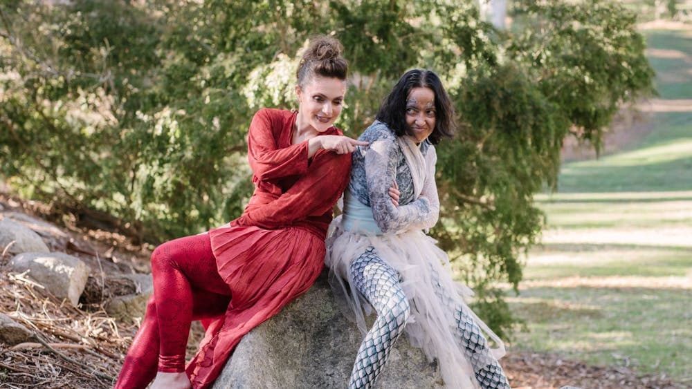 To magical characters playfully interacting, while sitting on a rock