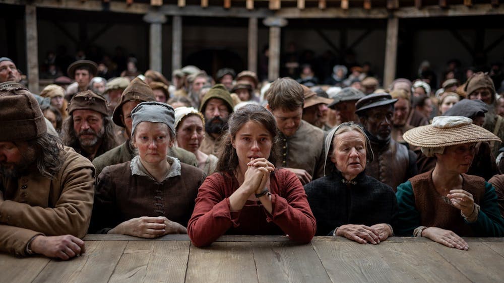 Crowd stands leaning on stage in Shakespeare's Globe Theatre